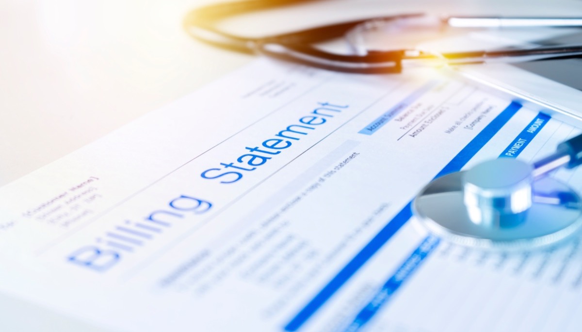A medical billing statement on a desk beside a stethoscope