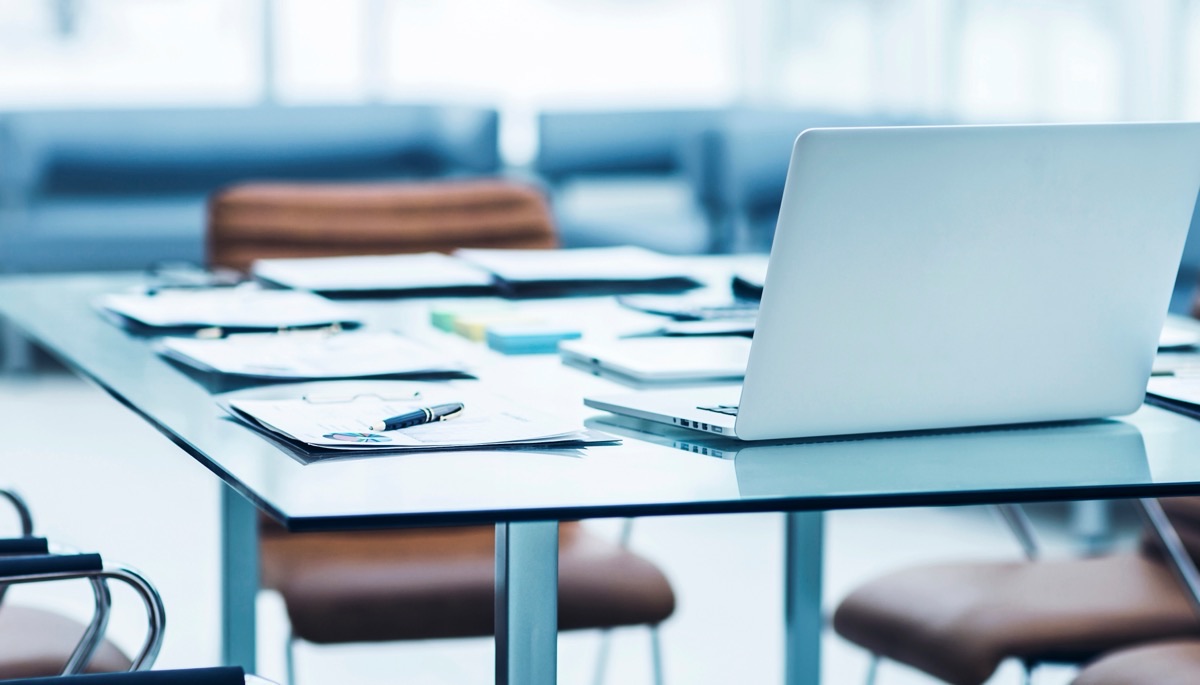 A laptop and documents on a meeting room table